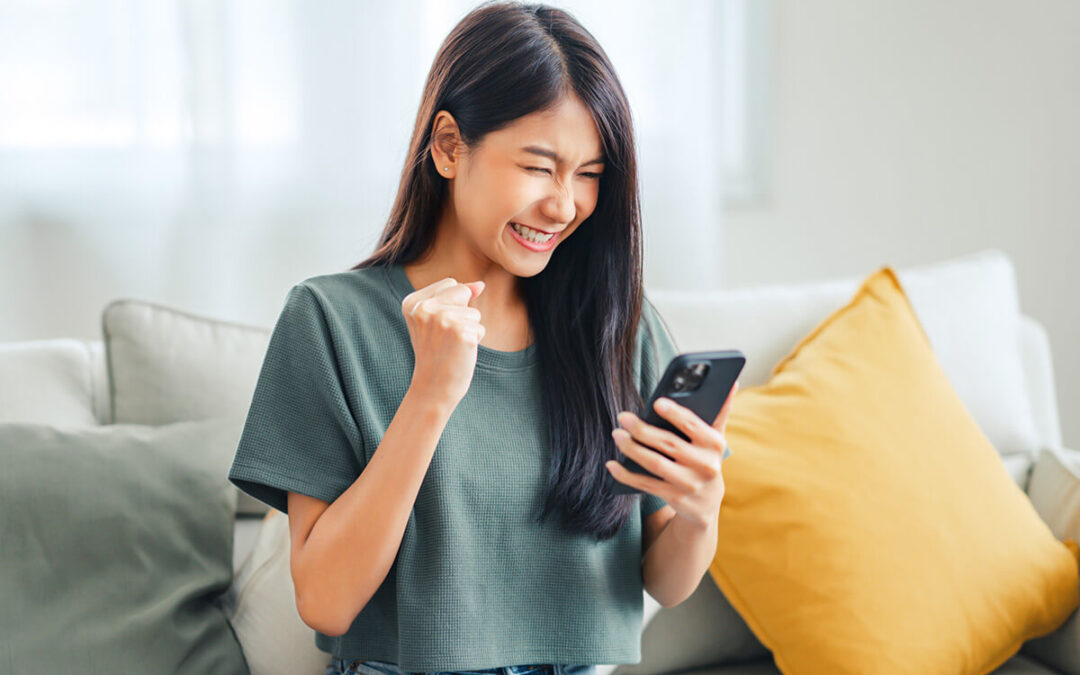 Excited young asian woman hold phone chatting